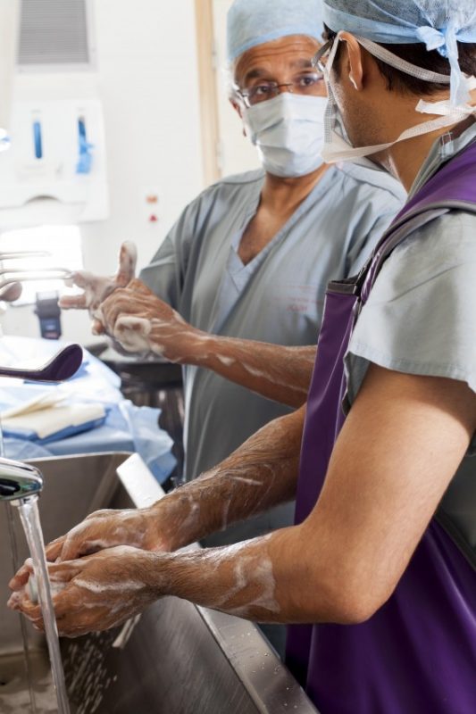 Two theatre staff in scrubs washing their hands