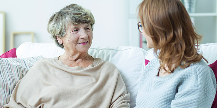 Photograph of a mother and daughter, sat on a sofa having a discussion