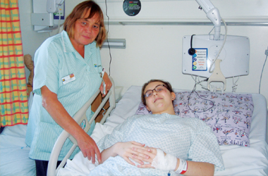 Ciaran laying in her ward bed, the ward hostess is with her