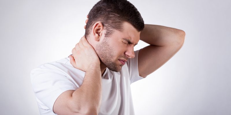 Image of a person holding their neck and base of head area with a painful expression on their face