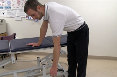 Leaning forwards the unaffected hand is placed on a table with the other arm relaxed to the side