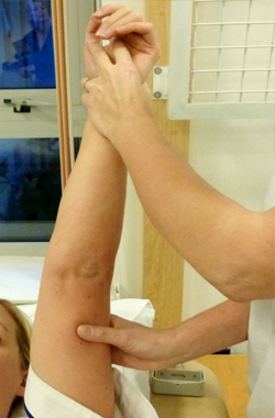 Laying down, the hand is being held and supported under the upper arm, the arm is pointing straight up - it has been rotate outwards slightly
