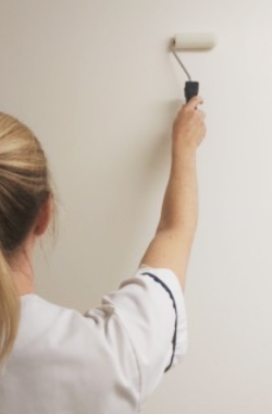 Paint roller held in the hand and against the wall