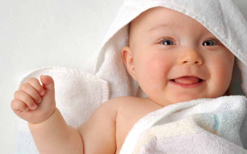 image of baby sat up eyes open and smiling 