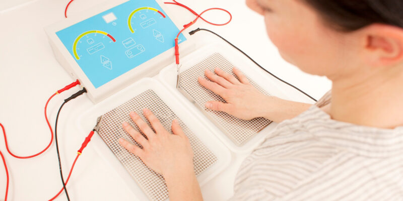 Patient has each hand placed in a shallow tray full of water. These trays have an electric current being passed through them by a machine.
