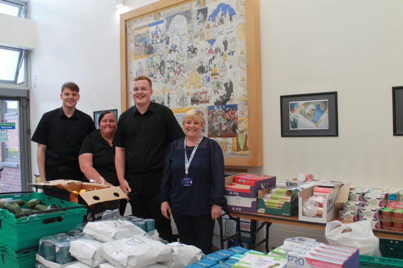 A group of people standing behind tables of food