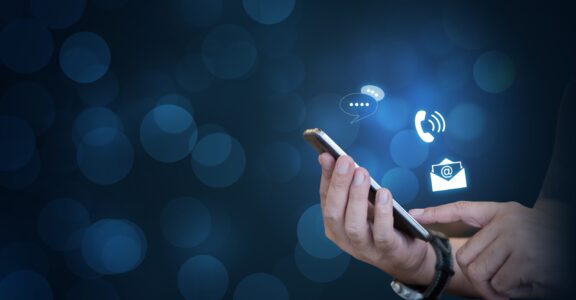 CONTACT US, Hand of a businessman holding a mobile smartphone with the icon. Contact us connection concept with copy space.