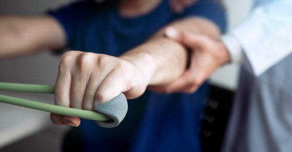 male physical therapist descent working with patient doing.