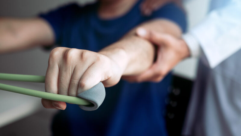 male physical therapist descent working with patient doing.
