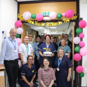 A group of people having their photo taken with a cake
