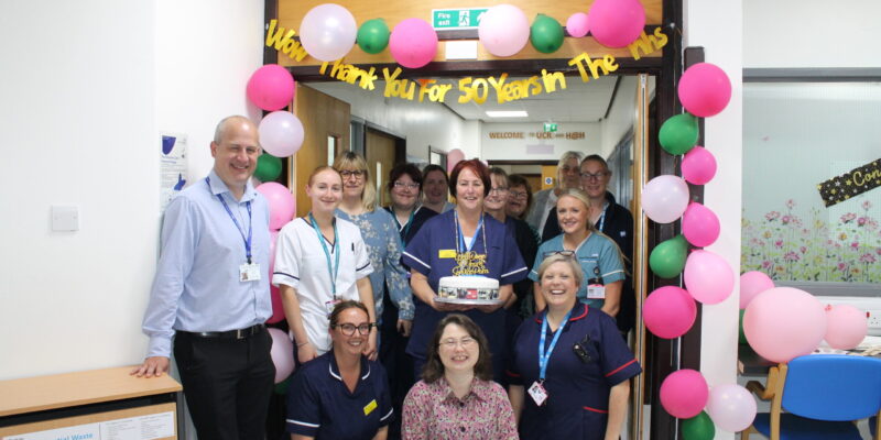 A group of people having their photo taken with a cake